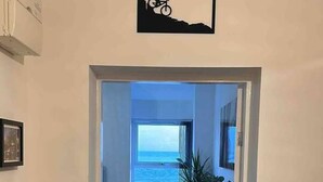 A hallway leading to a room with a view of the sea, a framed picture on the wall, and a plant. - Remarkable 1-bed Seaview Beach Apartment Barmouth (Barmouth)