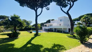 Un edifici modern de dues plantes amb piscina, envoltat de gespa i arbres ben cuidats.