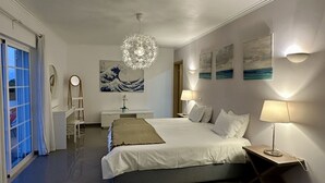 Un dormitori amb un llit gran, làmpades de nit, una petarrera, un mirall i obra d'art a les parets.
