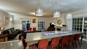Un saló modern amb zona de menjador, amb una gran taula illa, cadires vermelles i il·luminació penjant.