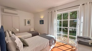 Un dormitorio con dos camas, una ventana y vistas a la vegetación.