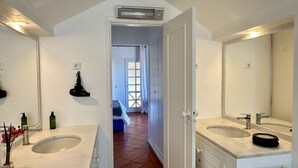 A bathroom with two sinks, a mirror, and a shower area.