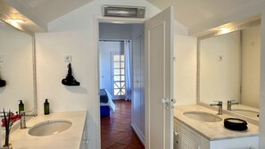 Une salle de bain avec deux lavabos, un miroir et un espace douche.