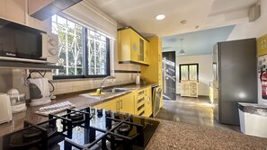 A modern kitchen with yellow cabinets, a stainless steel refrigerator, and a window with decorative ironwork. - Strip by Check-in Portugal (Albufeira)