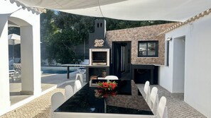 An outdoor dining area with a black table, white chairs, and a flower centerpiece. - Strip by Check-in Portugal (Albufeira)