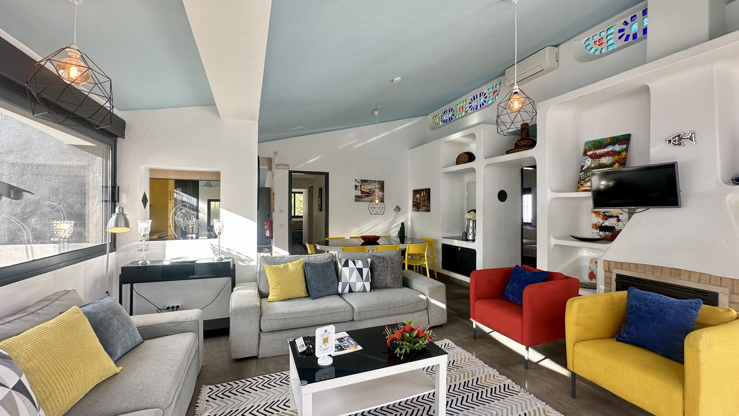 A modern living room with a sofa set, a red armchair, a yellow armchair, a coffee table, and a fireplace.