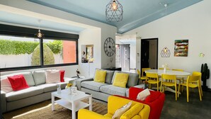 A modern living room with a grey sofa, yellow armchair, and a dining area with yellow chairs and a white table. - Strip by Check-in Portugal (Albufeira)