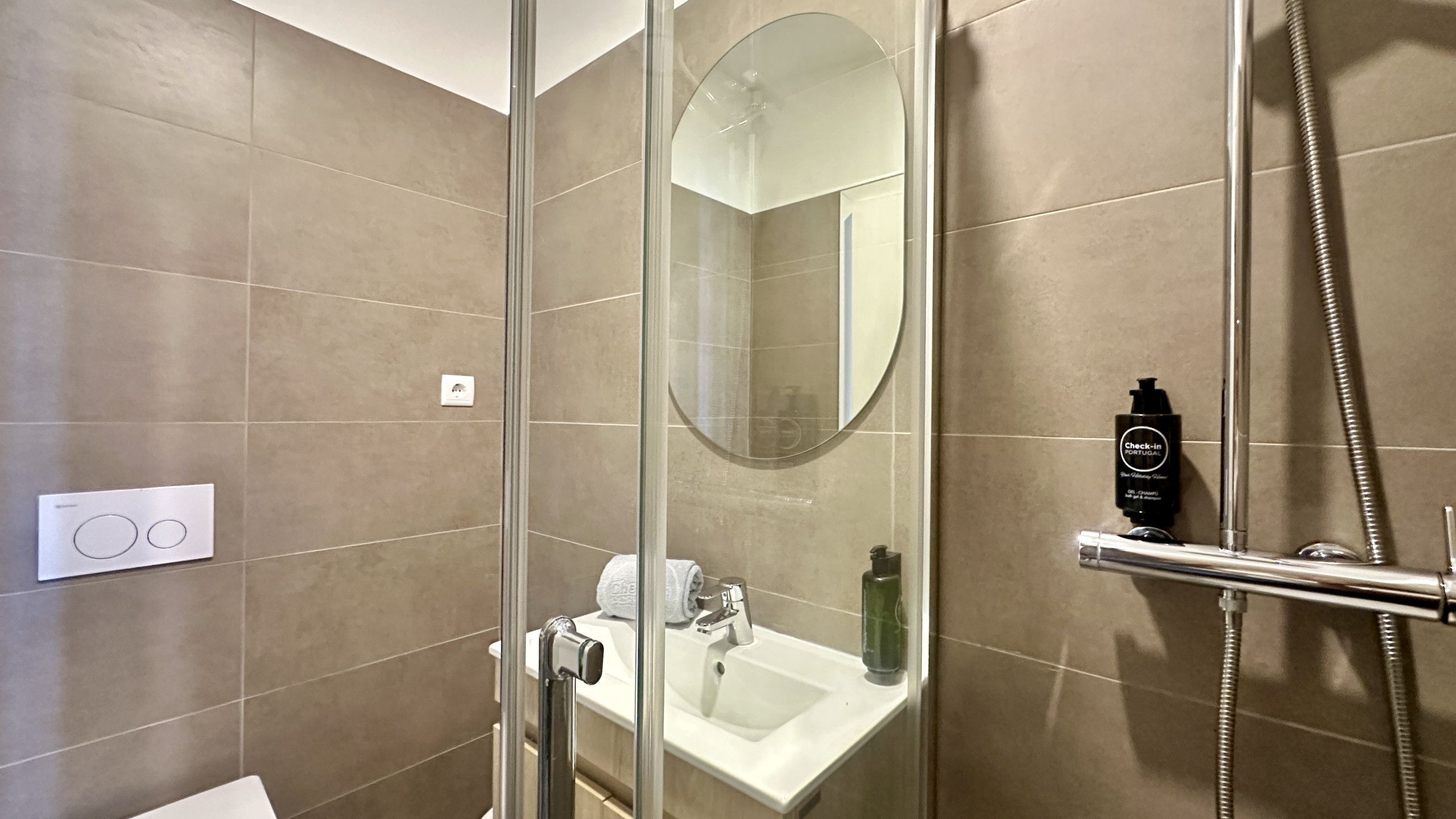 A modern bathroom with a glass-enclosed shower, a white sink, and a mirror.