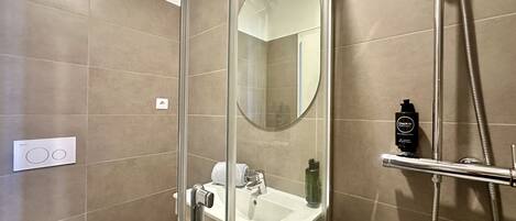 A modern bathroom with a glass-enclosed shower, a white sink, and a mirror.