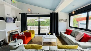 A modern living room with a fireplace, a sofa, a red armchair, a coffee table, and a television. - Strip by Check-in Portugal (Albufeira)