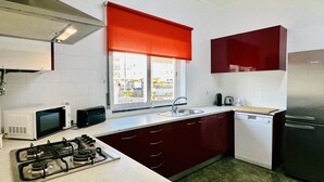 Una cocina compacta con estufa a gas, microondas, fregadero y refrigerador.