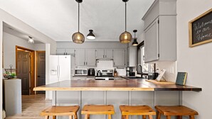 A modern kitchen with a central island, bar stools, and pendant lighting.