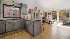 A modern kitchen with grey cabinets, a wooden countertop, and pendant lighting.