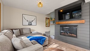 A modern living room with a sectional sofa, a fireplace, and a mounted TV.