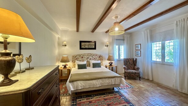 A bedroom with a bed, bedside lamps, a chair, a window with curtains, and a picture on the wall. - Sol by Check-in Portugal (Vilamoura)