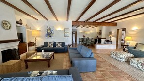 Ein geräumiges Wohnzimmer mit Kamin, Sofas, einem Couchtisch und einem Essbereich mit Stühlen und Tisch.