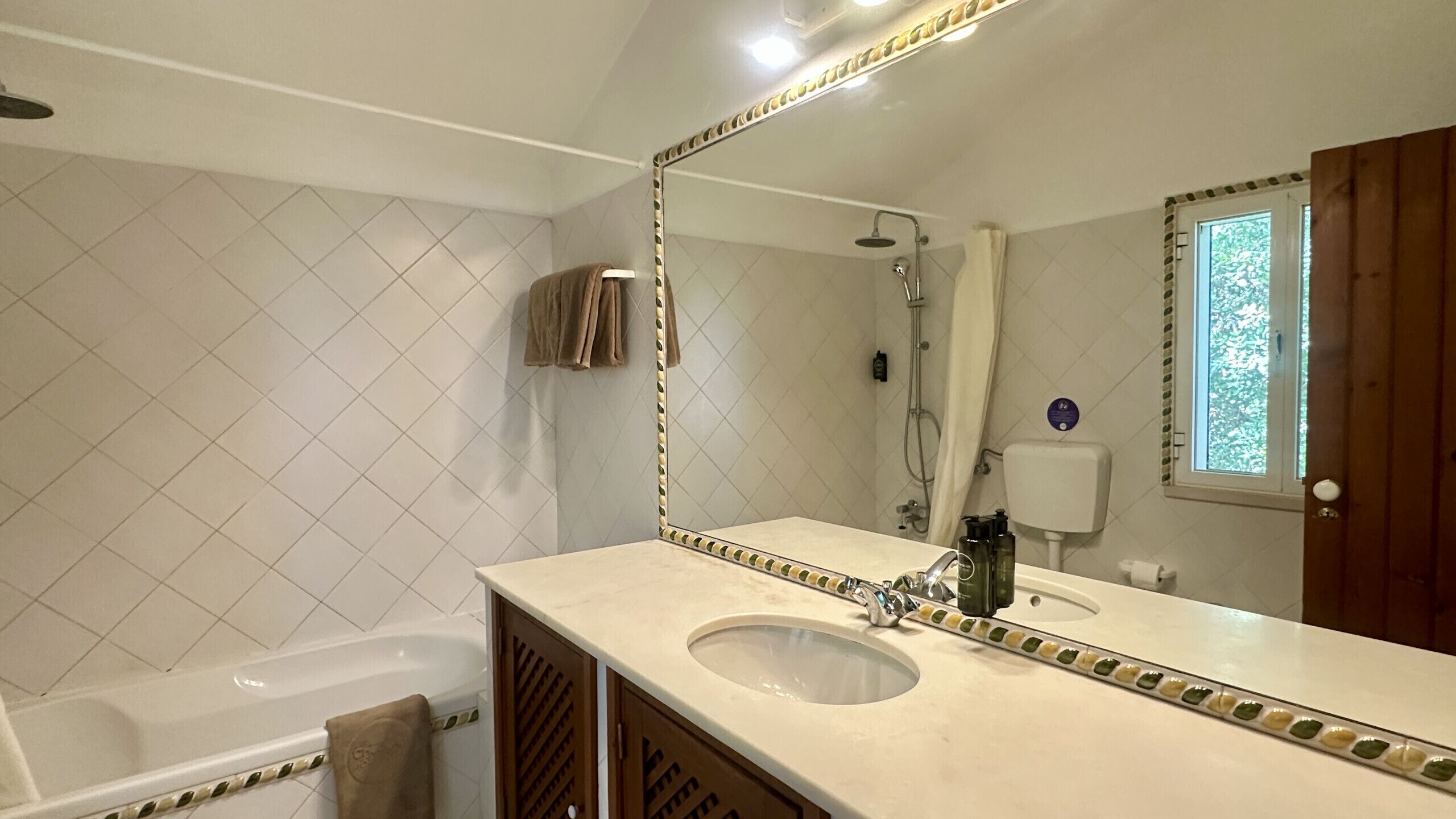 A bathroom with a bathtub, a sink with a large mirror, and a shower.