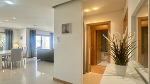Une chambre d’hôtel moderne comprenant un lit, un coin repas et un couloir menant à la salle de bain.
