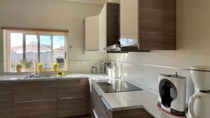 Een moderne keuken met een inbouw vaatwasser, een raam met plantenbakken en uitzicht op buiten.