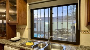 A kitchen with a double sink, wooden cabinets, and a view of a patio with outdoor furniture.