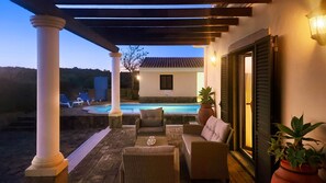 Un espacio al aire libre cubierto con piscina, sillas de descanso y un conjunto de asientos.