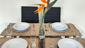 A dining table set with plates, cutlery, and a decorative bird of paradise flower in a clear vase. - A 10 Minutos das Piscinas Naturais do Porto Moniz. Aceito Animais de Estimação (Ribeira da Janela)