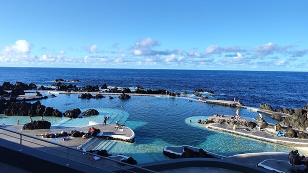 A resort pool area with clear water, surrounded by rocky formations and a view of the ocean. - A 10 Minutos das Piscinas Naturais do Porto Moniz. Aceito Animais de Estimação (Ribeira da Janela)