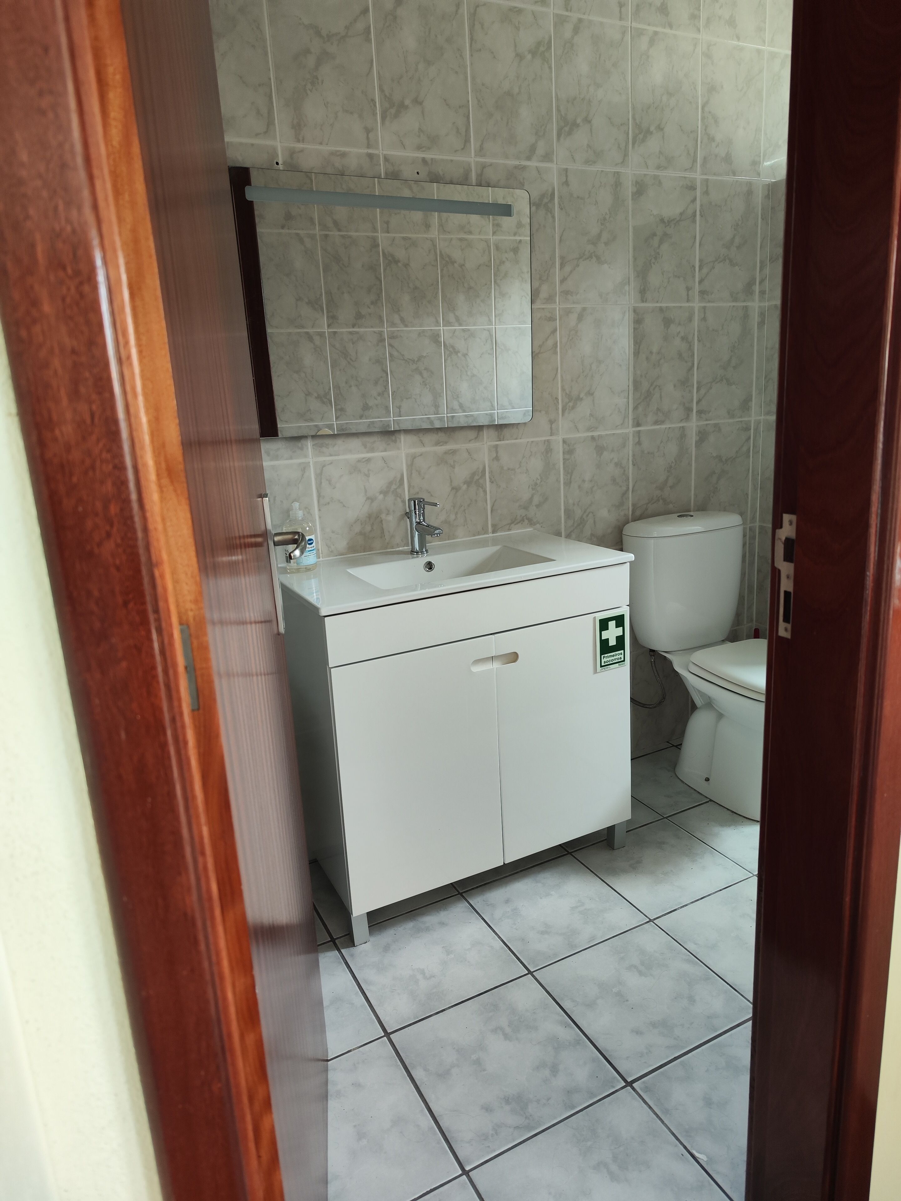 Une salle de bain avec un lavabo blanc, un miroir et des toilettes.