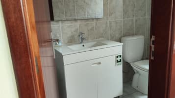 Une salle de bain avec un lavabo blanc, un miroir et des toilettes.