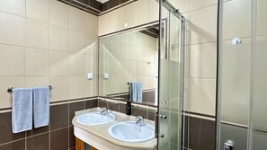 A bathroom with two sinks, a mirror, and a glass shower enclosure.