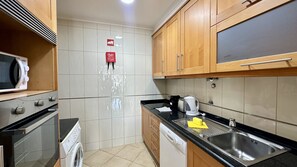 Una cocina equipada con microondas, estufa, lavadora, pileta y alacenas.