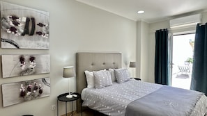 Une chambre à coucher avec un lit, une table de chevet, une lampe et des œuvres d’art accrochées au mur.