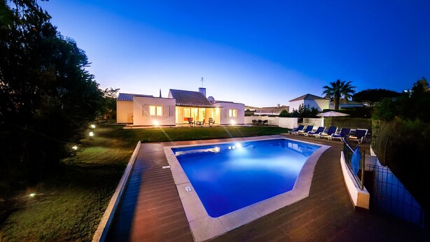 Uma casa moderna com piscina, área de estar ao ar livre e um pátio bem iluminado.