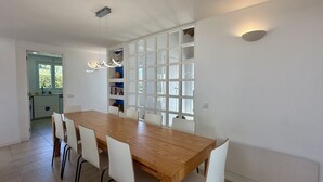 Uma cozinha moderna com armários brancos, uma mesa de jantar de madeira e uma estante embutida.