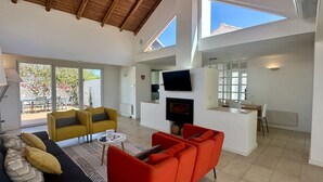 Uma sala de estar ampla, com design moderno, com um conjunto de sofás, uma poltrona vermelha e uma lareira.