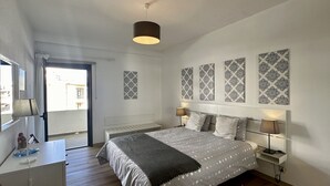 A modern bedroom with a bed, bedside lamps, a desk, and a view of the outside. - Medronheira by Check-in Portugal (Albufeira)