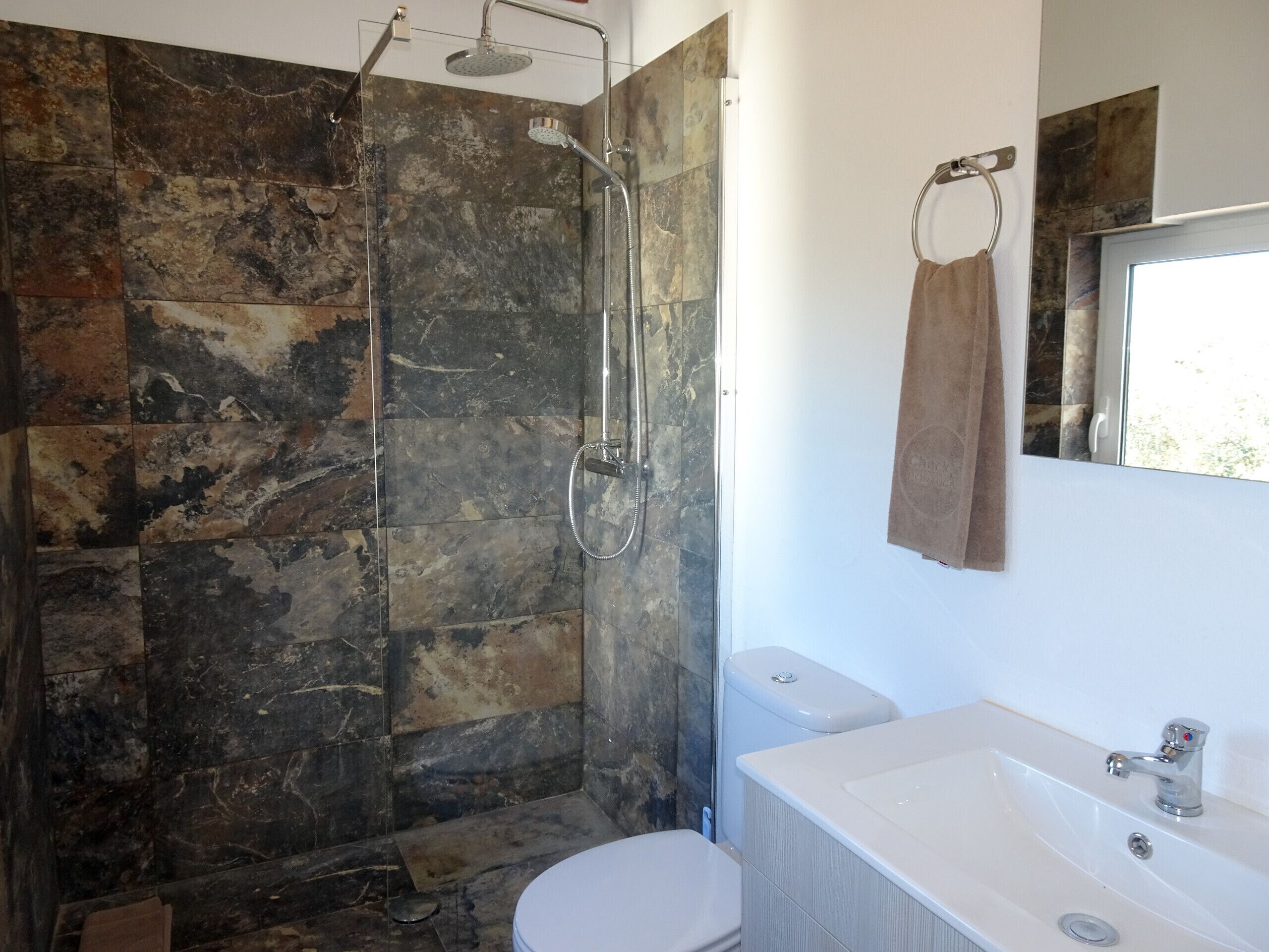 Une salle de bain avec douche, toilettes et lavabo.