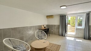 A room with two wicker chairs, a small table, a ceiling light, a window with curtains, and a wall-mounted air conditioner. - Abby by Check-in Portugal (Albufeira)