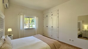 Une chambre à coucher comprenant un lit, une fenêtre, une armoire et une table de chevet avec une lampe.