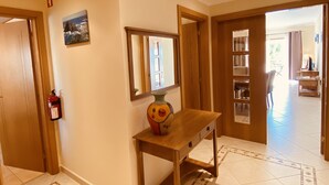A hallway with a wooden console table, a fire extinguisher, and a mirror.