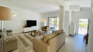 Una sala de estar moderna con una televisión de pantalla plana, un sofá, una mesa de centro y un comedor.
