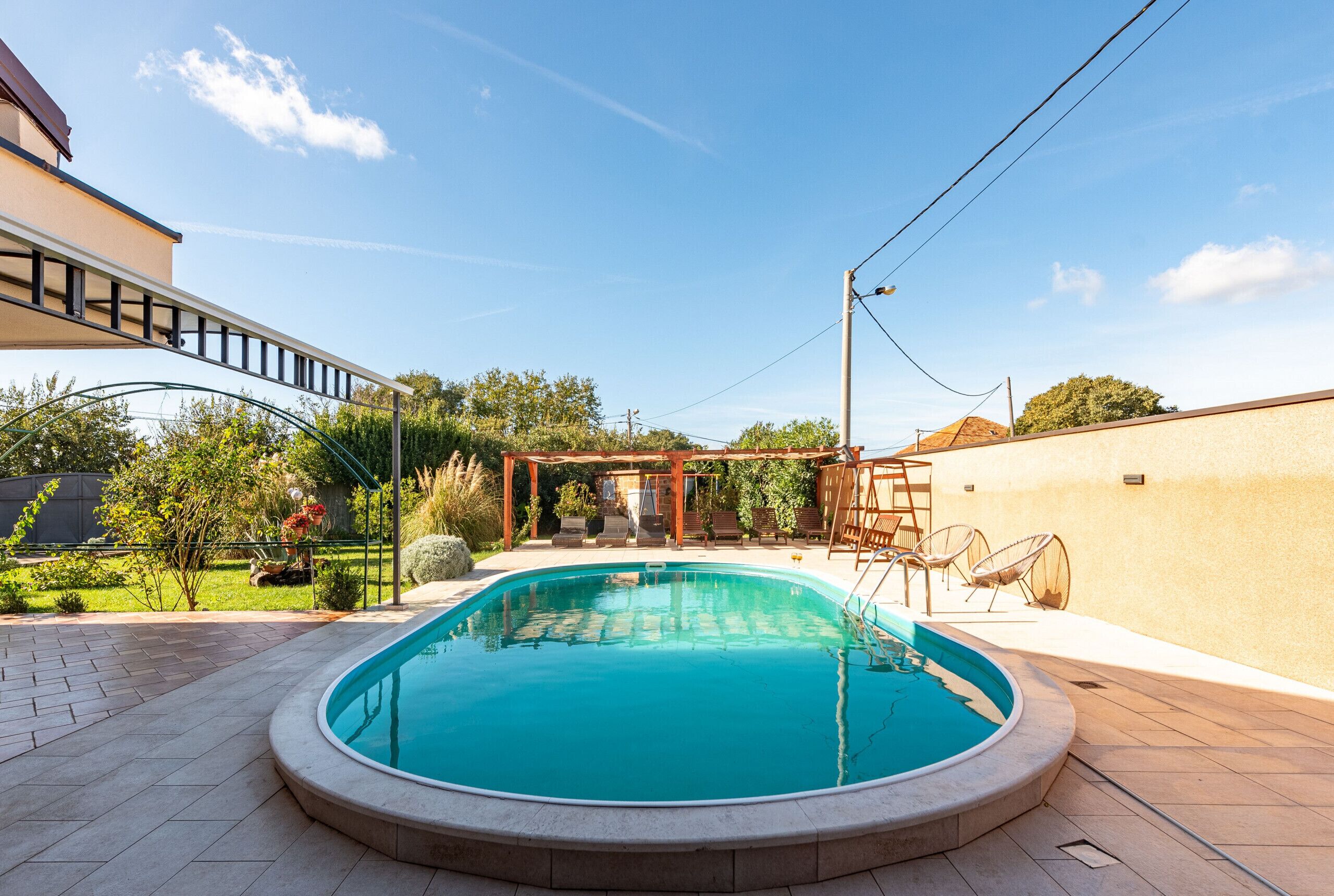 A swimming pool with a pergola and outdoor seating area.