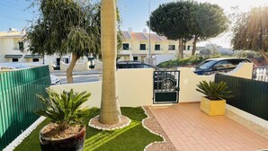 A residential area with a paved patio, a green fence, and a gated entrance. - Mosqueira by Check-in Portugal (Albufeira)