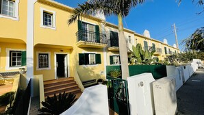 A yellow building with green shutters, a balcony, and a staircase leading to the entrance. - Mosqueira by Check-in Portugal (Albufeira)