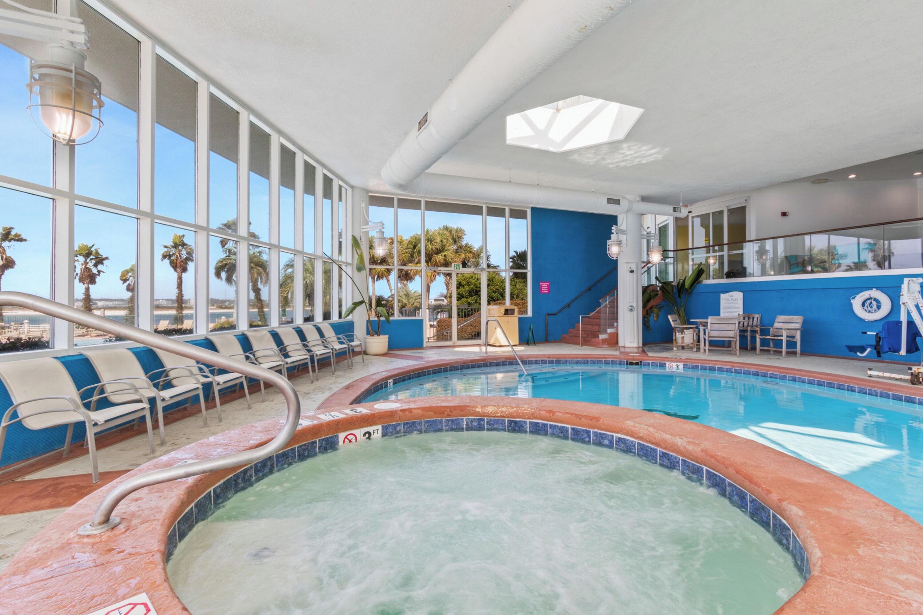 Una piscina interior con vistas despejadas a palmeras y una pared azul.