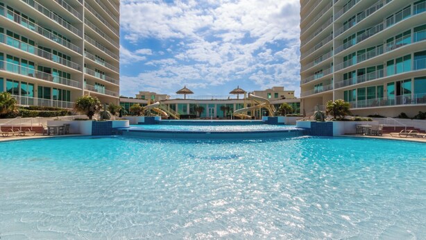 A large swimming pool surrounded by modern buildings with multiple balconies. - Caribe D814 (Orange Beach)