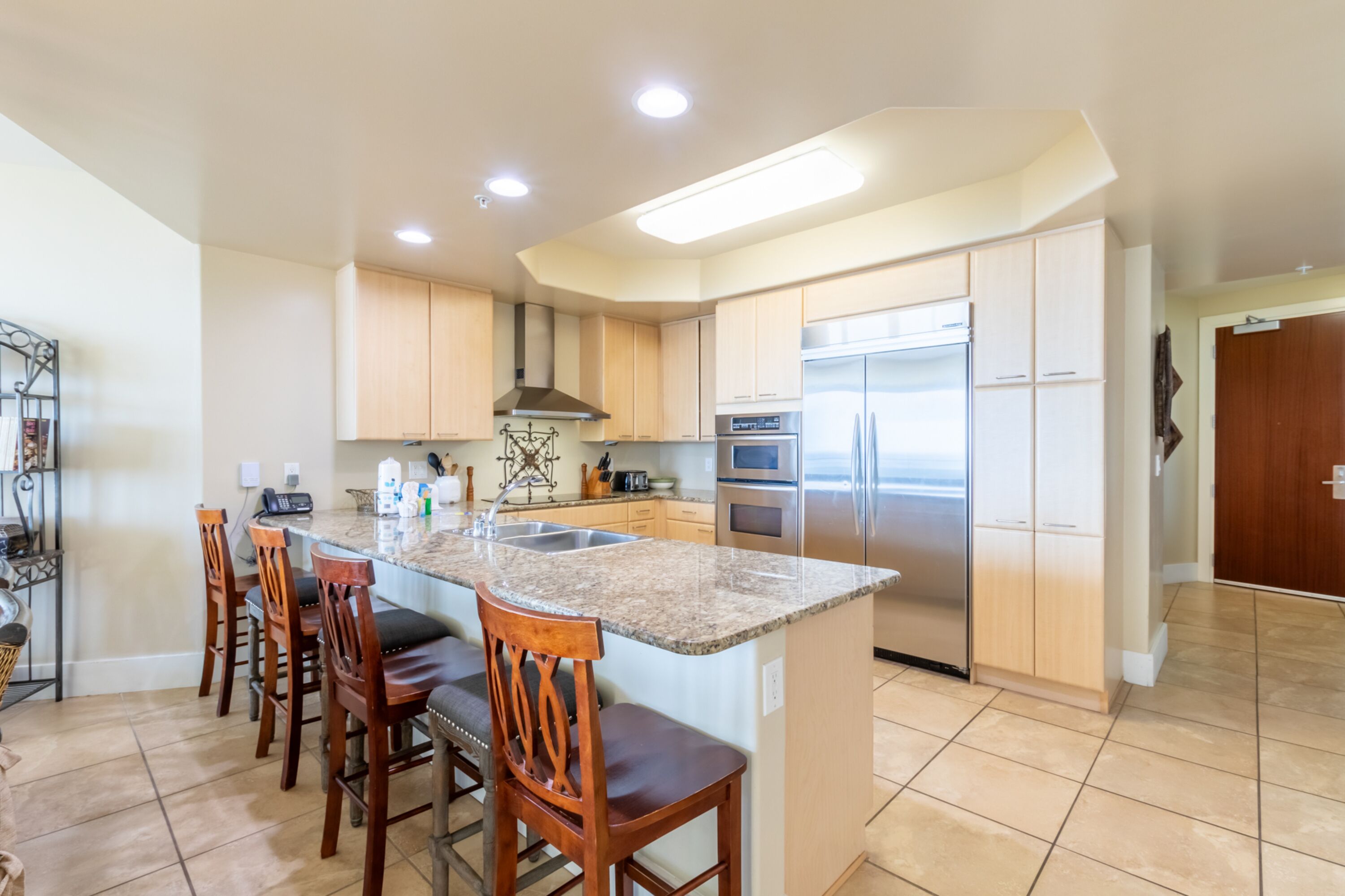 A modern kitchen with a central island, stainless steel appliances, and wooden bar stools.