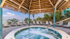 A hot tub under a wooden gazebo with lounge chairs and palm trees in the background. - Caribe D814 (Orange Beach)