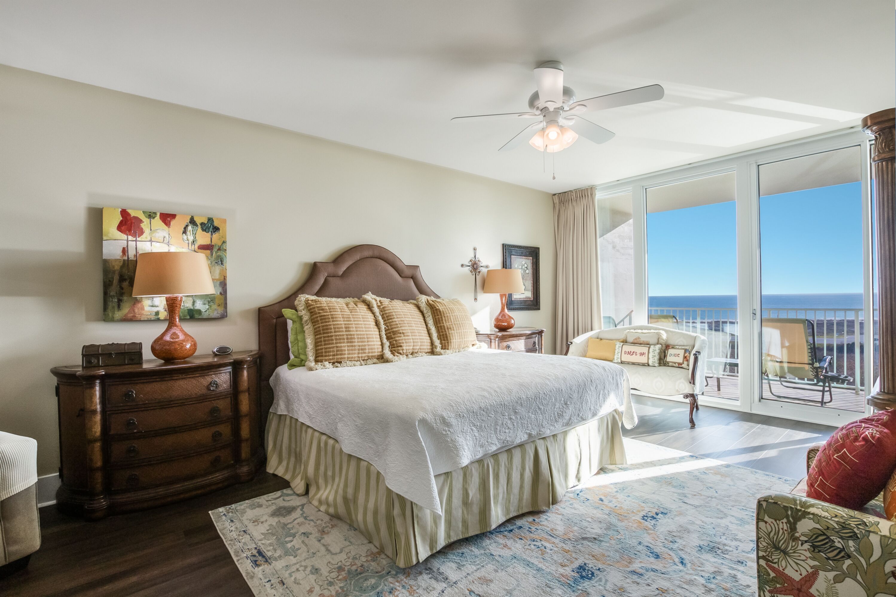 A bedroom with a bed, dresser, and a view of the ocean.