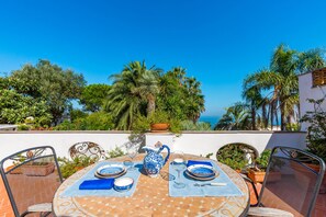 A table set outdoors with a view of the sea, surrounded by chairs and potted plants. - Capri Turquoise by Napoliapartments (Capri)